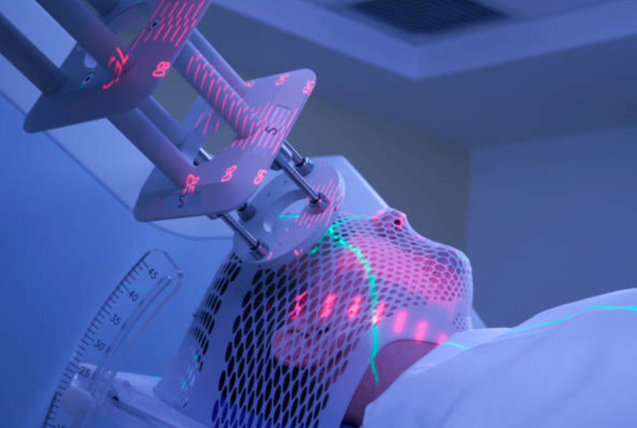 Robot-assisted medical device with a perforated housing and neon pink/green alignment lights guiding a patient in a blue-lit treatment room.