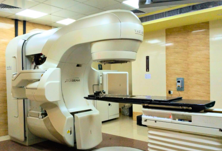 Varian TrueBeam linear accelerator in a radiation therapy room with a patient treatment table.
