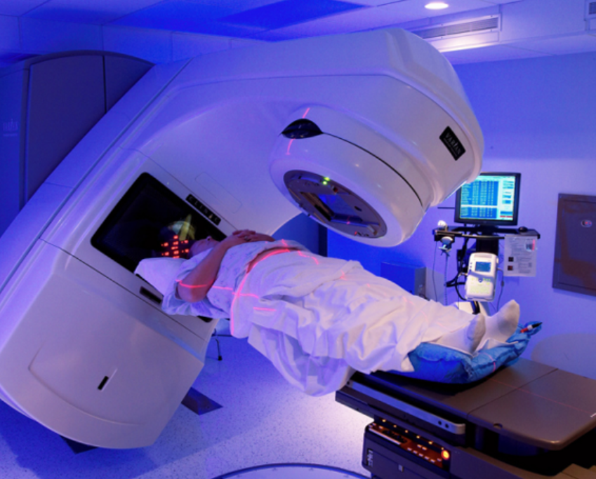 Patient lying on an MRI table as the large imaging bore approaches in a blue-lit room.