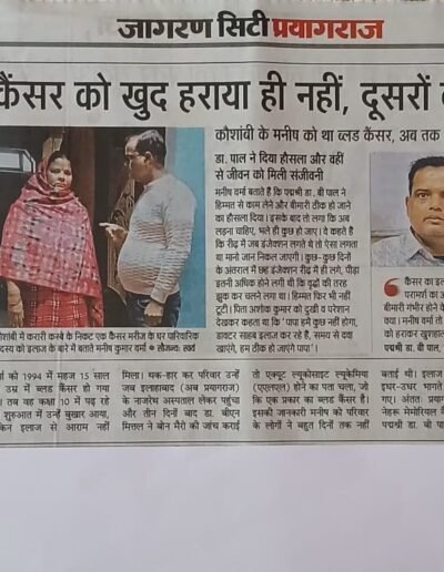 Hindi newspaper front-page article about defeating cancer; image shows a couple (woman in pink shawl, man in light sweater) and a man’s portrait on the right.